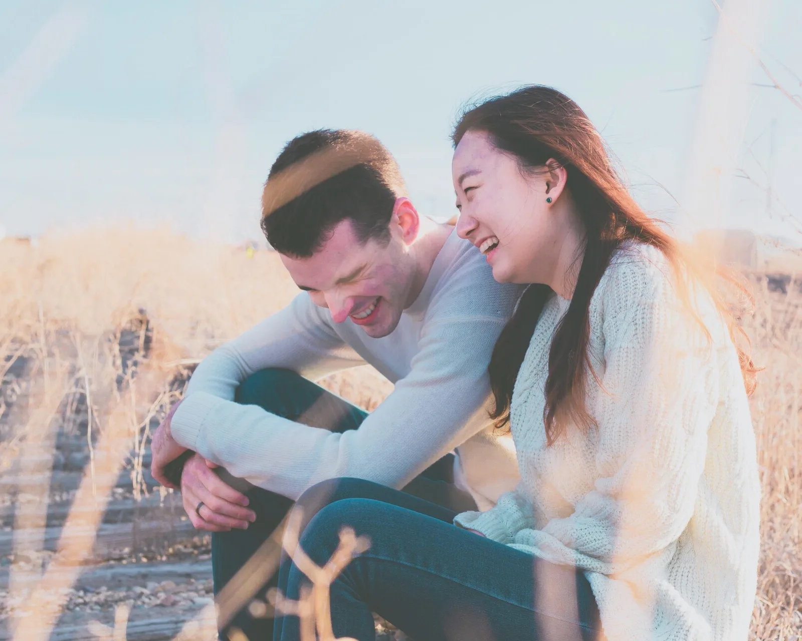 People smiling together in an open field on a bright day.