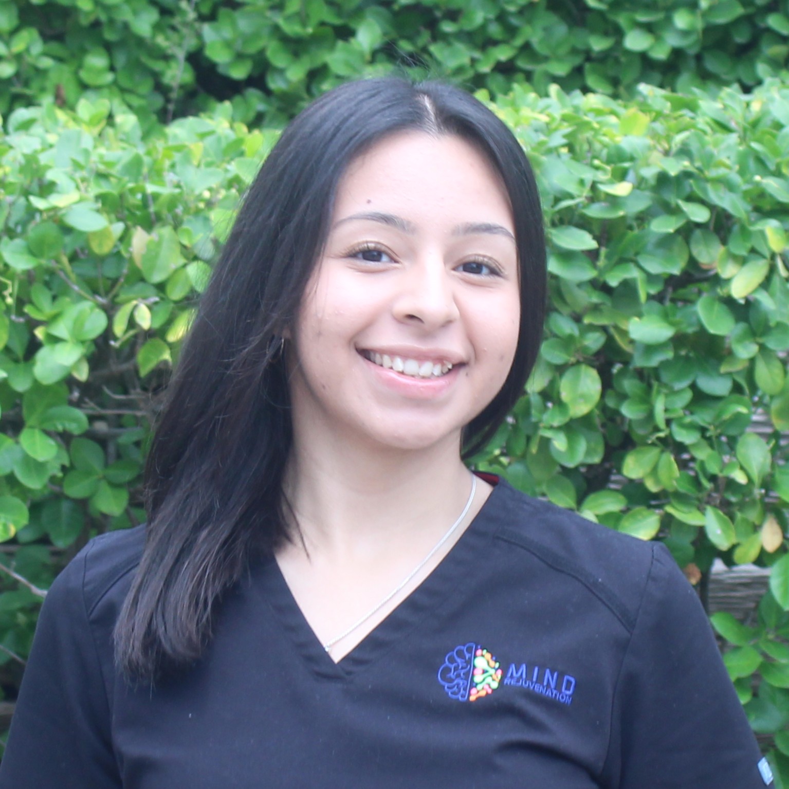 Nancy, Medical Assistant (MA) and Certified Nursing Assistant (CNA) at Mind Rejuvenation, smiling in branded attire outdoors. Featured on the Meet Our Team page to reflect attentive care, clinical support, and a warm presence in patient wellness.