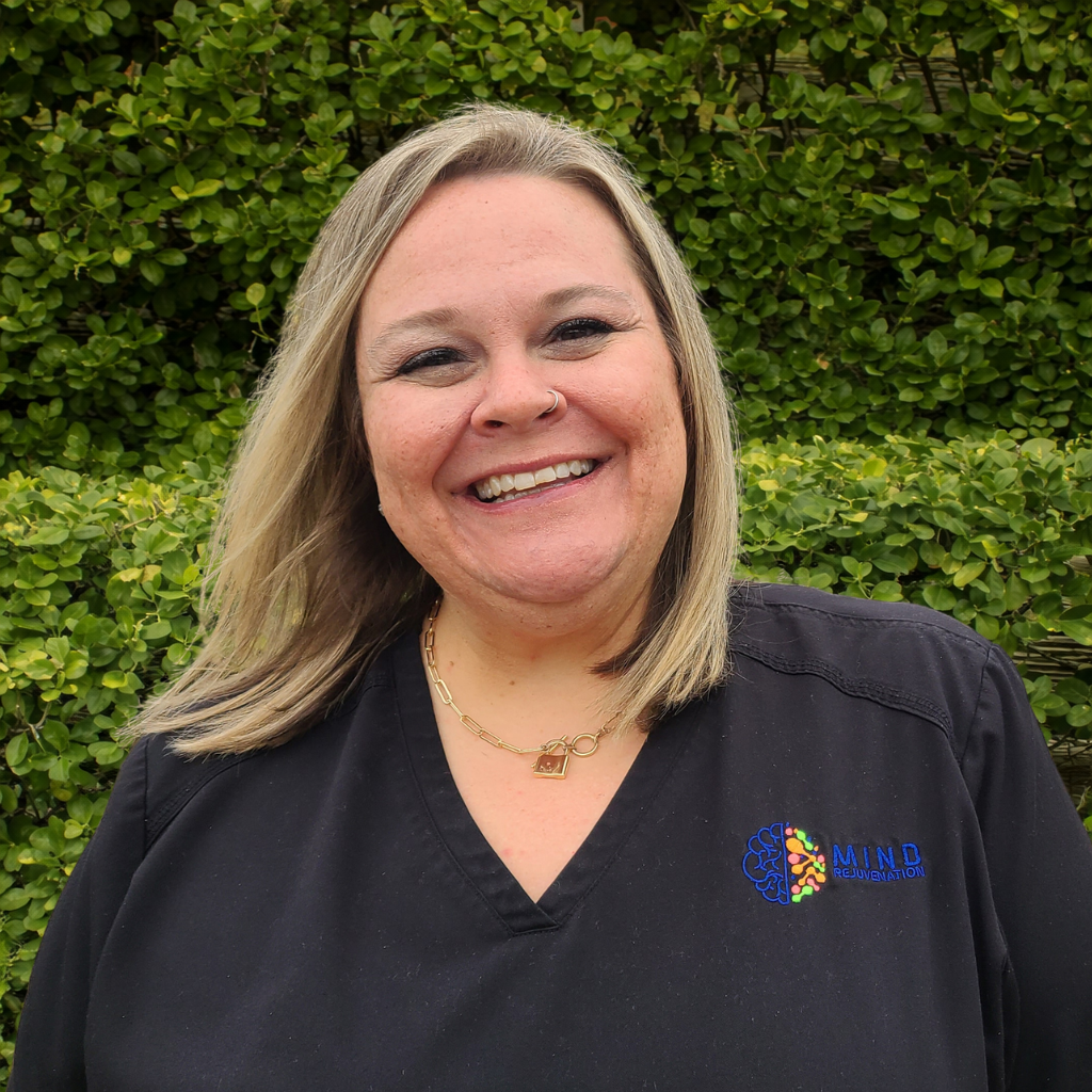 Christie, Licensed Practical Nurse (LPN) at Mind Rejuvenation, smiling in branded attire outdoors. Featured on the Meet Our Team page to reflect attentive care, clinical support, and a warm presence in patient wellness.