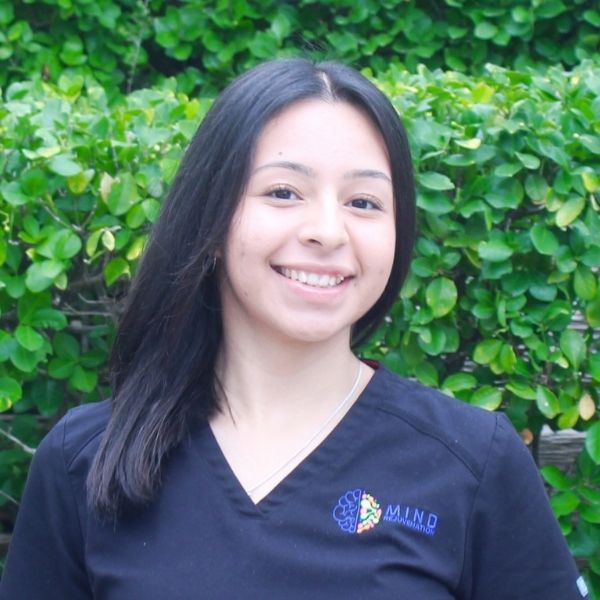 Nancy, Medical Assistant (MA) and Certified Nursing Assistant (CNA) at Mind Rejuvenation, smiling in branded attire outdoors. Featured on the Meet Our Team page to reflect attentive care, clinical support, and a warm presence in patient wellness.
