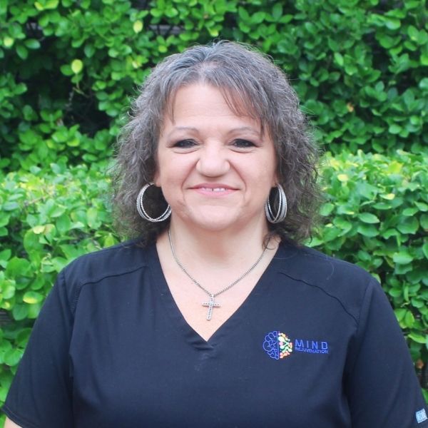 Peggy Shearl, Office Manager, Billing Specialist, and Prior Authorization Coordinator at Mind Rejuvenation, smiling in branded attire outdoors. Featured on the Meet Our Team page to reflect dedication, warmth, and behind-the-scenes expertise in patient care.